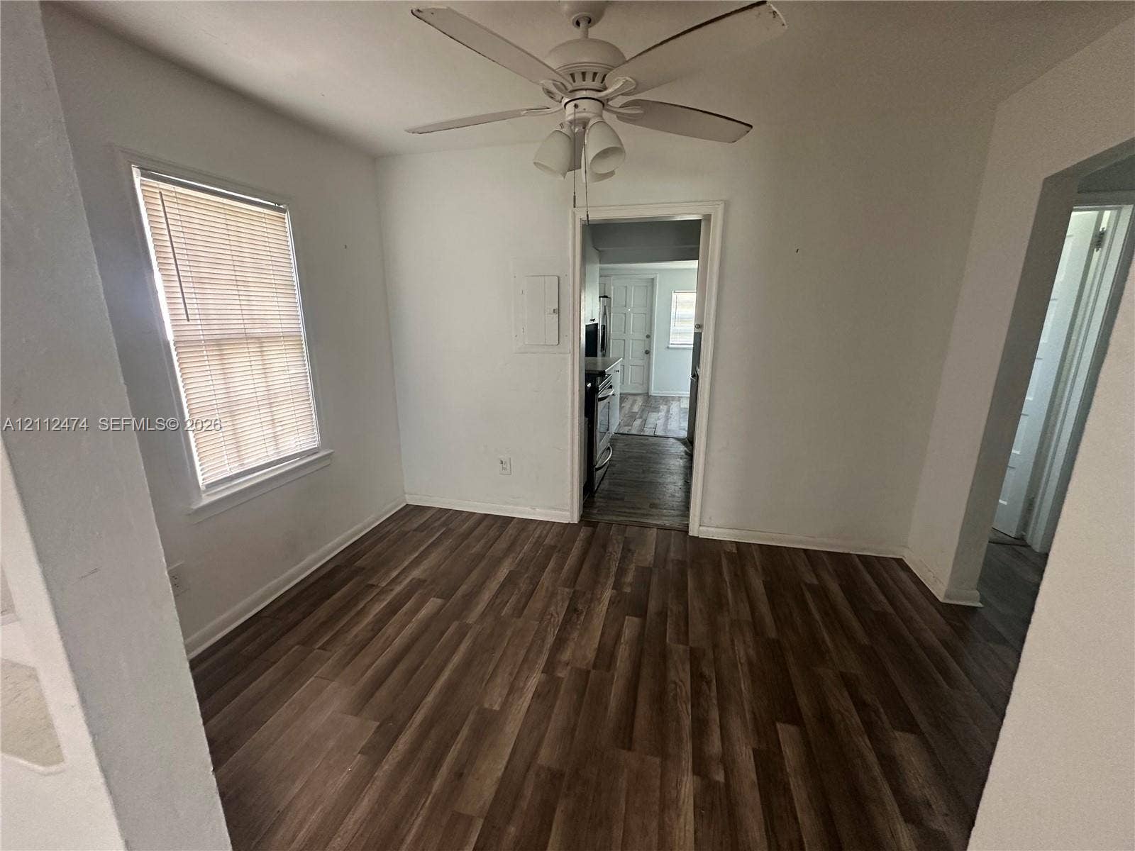 Interior space featuring wood-finish flooring, a ceiling fan with integrated lighting, and a single-pane window with blinds