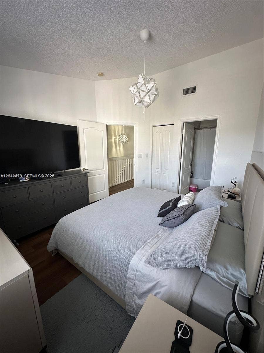 Vaulted ceiling featuring a geometric pendant light fixture, wood-finish flooring, and multi-panel interior doors