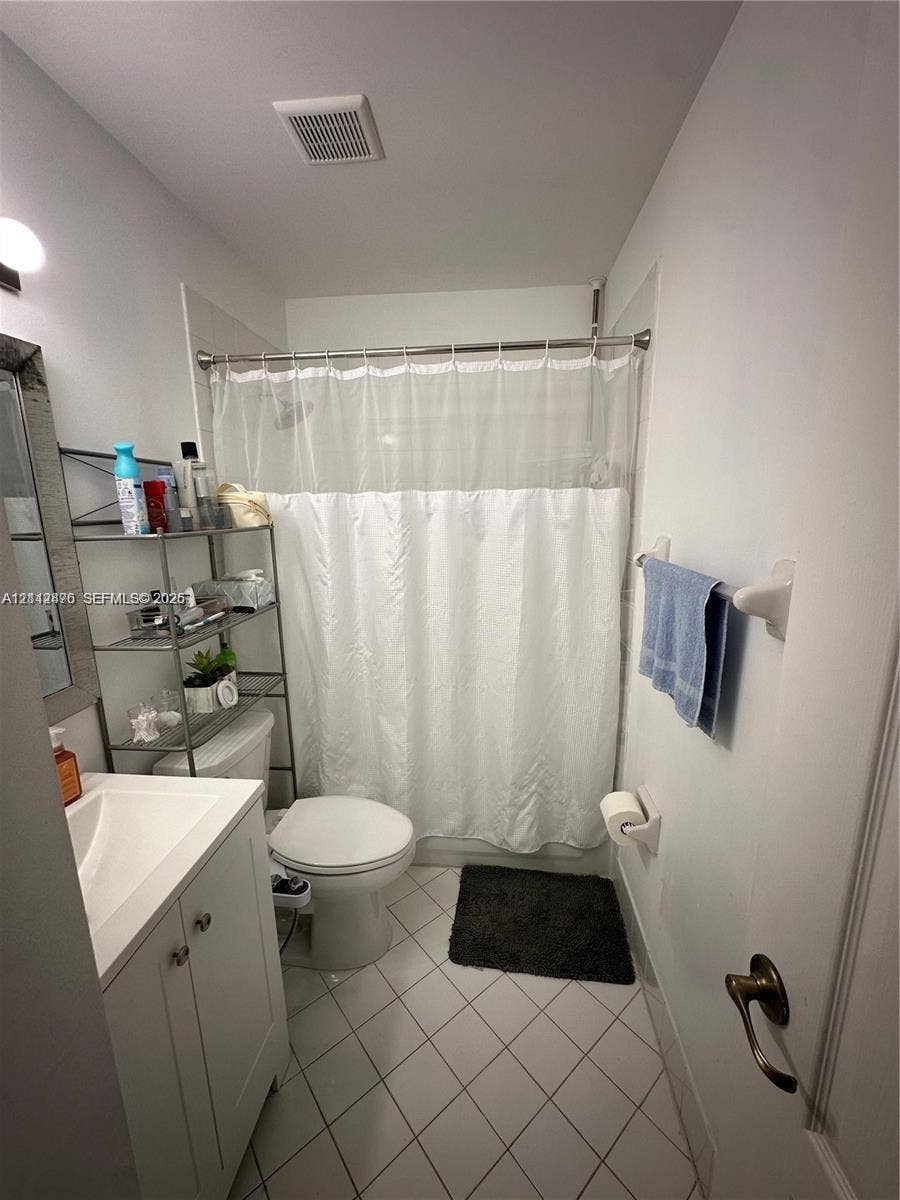 Bathroom featuring a white vanity cabinet with a rectangular integrated sink, a combination shower and tub enclosure, and white diagonal tile flooring
