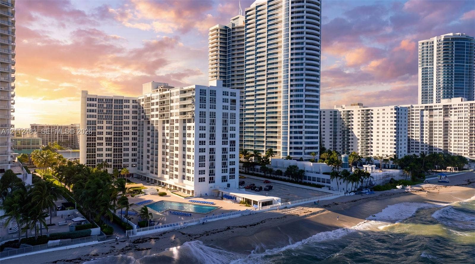 3505 S Ocean Drive, #1101, Hollywood, FL 33019 High-rise residential tower featuring a multi-story glass facade, an outdoor swimming pool, direct coastal frontage, and surface parking