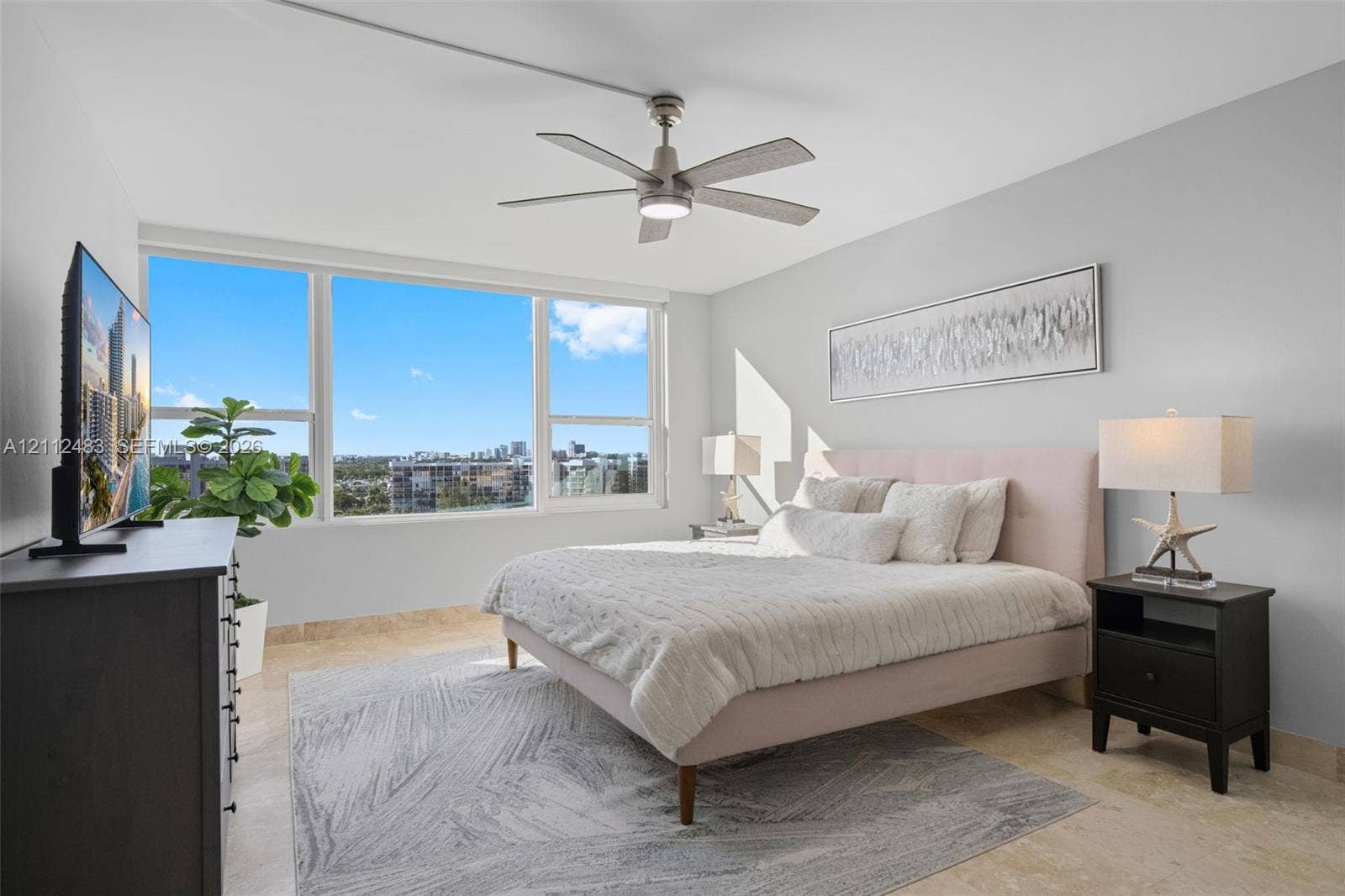 3505 S Ocean Drive, #1101, Hollywood, FL 33019 Neutral-toned room featuring expansive windows, stone flooring, and a modern ceiling fan with an integrated light fixture