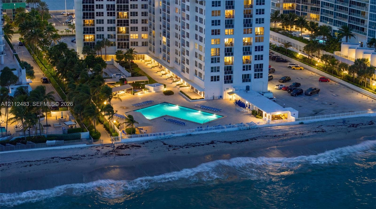 3505 S Ocean Drive, #1101, Hollywood, FL 33019 High-rise building featuring a swimming pool, paved sundeck, landscaped grounds with mature palm trees, and direct oceanfront positioning