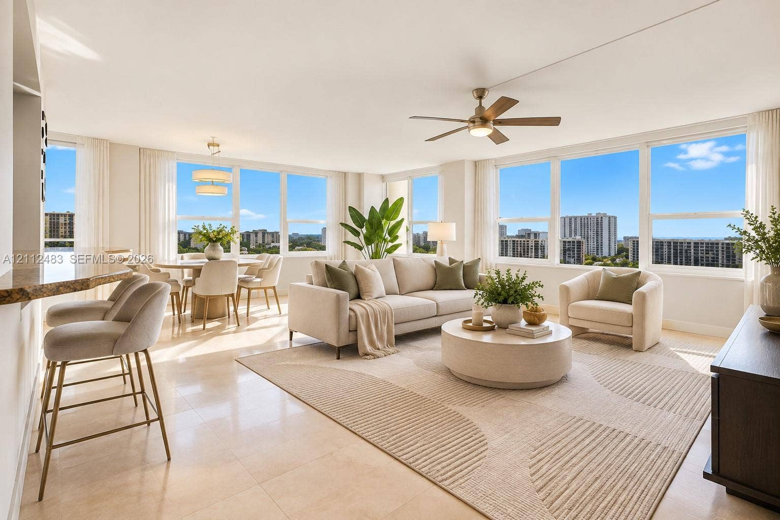 3505 S Ocean Drive, #1101, Hollywood, FL 33019 Open-concept interior featuring large-format stone flooring, expansive floor-to-ceiling windows, integrated breakfast bar with stone countertop, multi-blade ceiling fan, and tiered modern chandelier