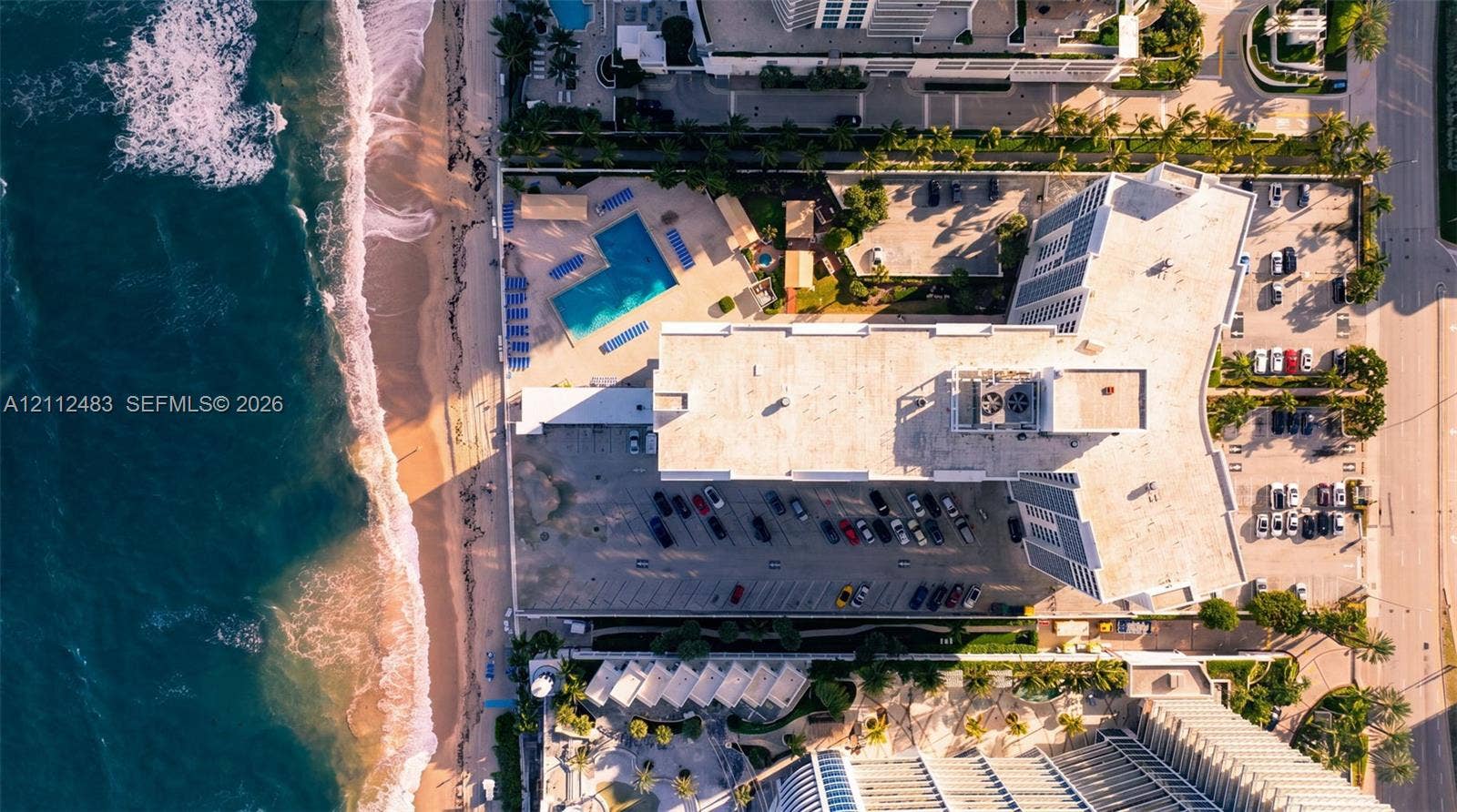 3505 S Ocean Drive, #1101, Hollywood, FL 33019 Aerial perspective featuring direct oceanfront access, a coastal pool, surface parking, and manicured grounds