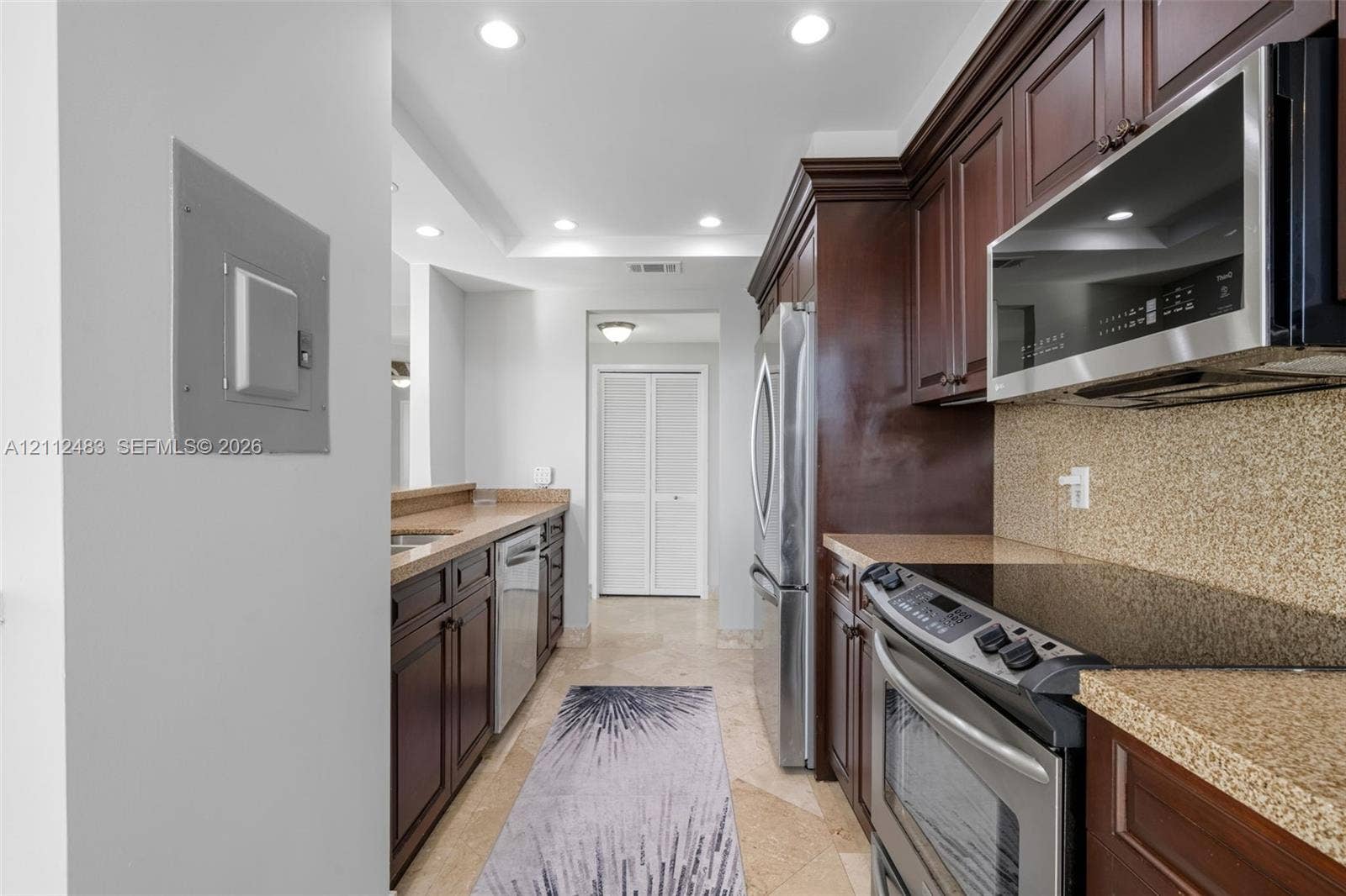 3505 S Ocean Drive, #1101, Hollywood, FL 33019 Kitchen featuring dark wood cabinetry, stone countertops, stainless steel appliances, and stone flooring