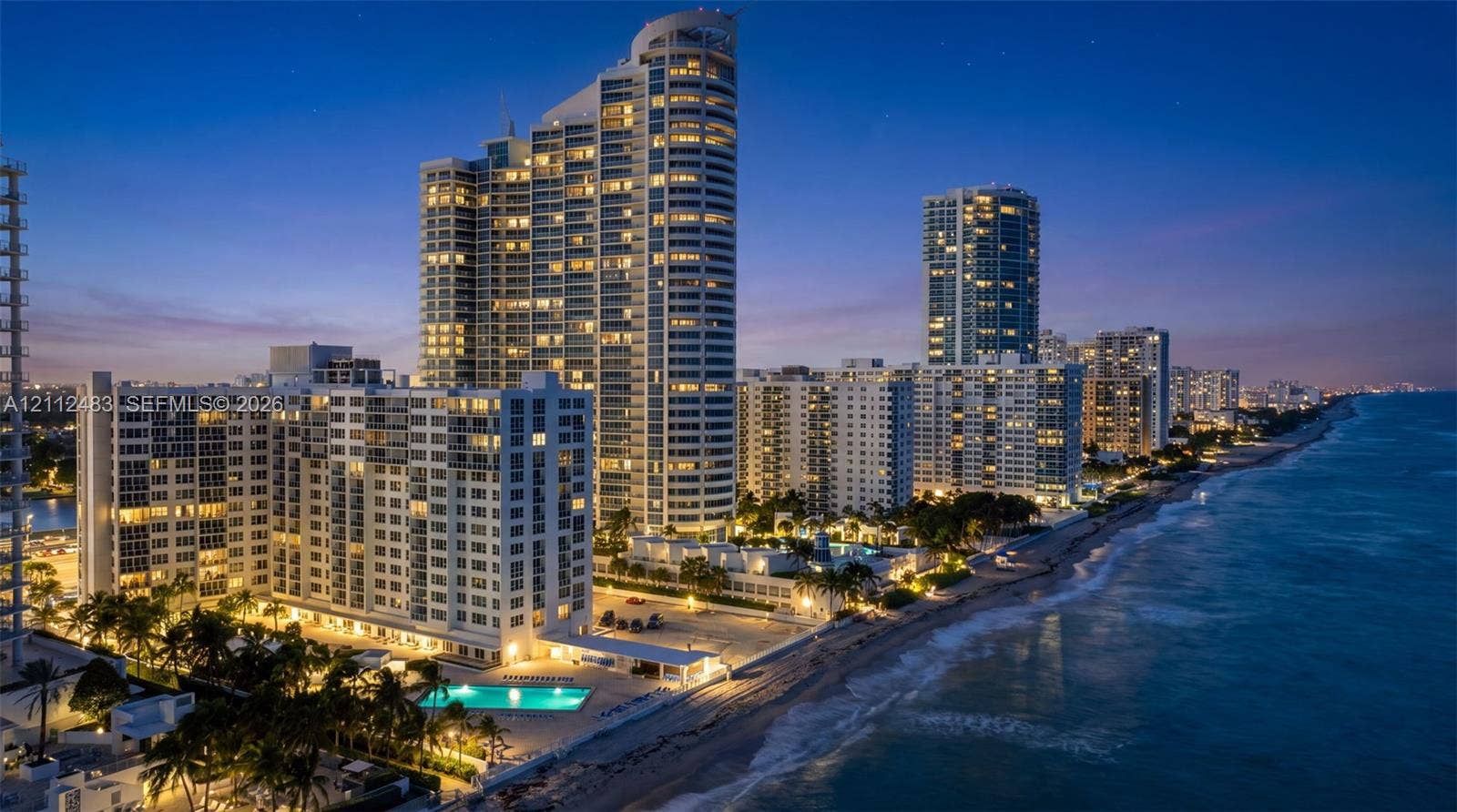 3505 S Ocean Drive, #1101, Hollywood, FL 33019 High-rise residential tower featuring glass-facade architecture, direct oceanfront positioning, ground-level swimming pool, and manicured palm tree landscaping