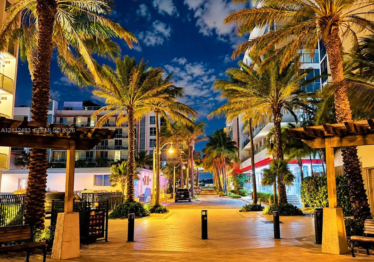3505 S Ocean Drive, #1101, Hollywood, FL 33019 Exterior pedestrian walkway featuring stone-paved paths, wood-frame pergolas, mature palm trees, and modern multi-story structures
