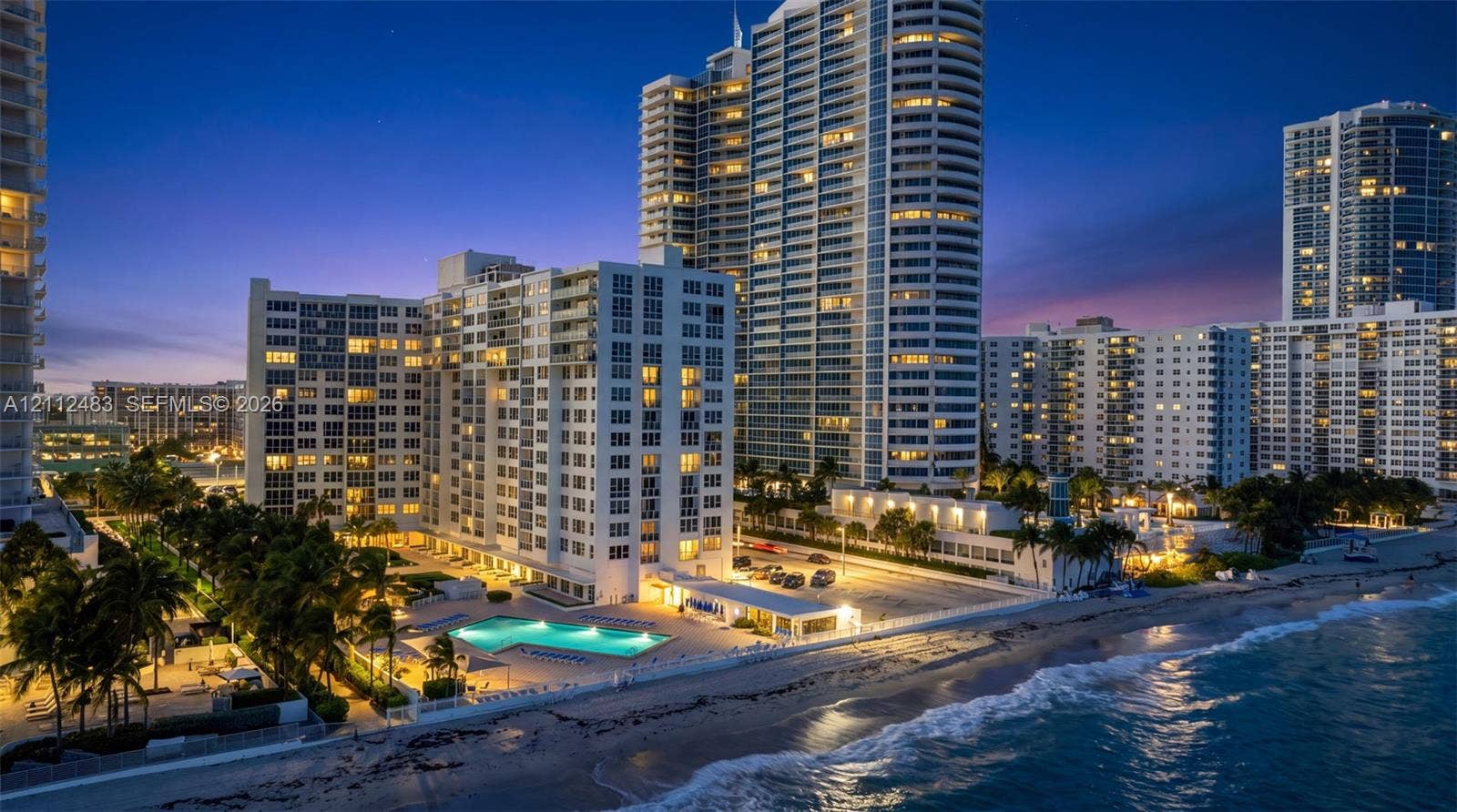3505 S Ocean Drive, #1101, Hollywood, FL 33019 High-rise residential complex featuring direct beach access, an outdoor swimming pool, integrated parking area, and palm tree landscaping