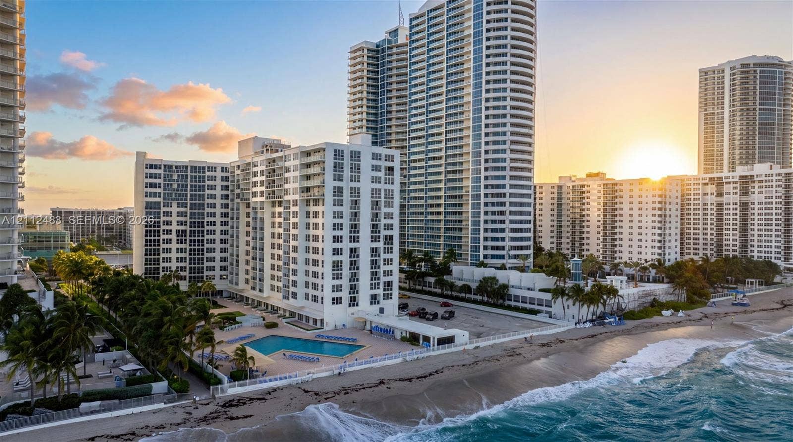 3505 S Ocean Drive, #1101, Hollywood, FL 33019 High-rise residential building featuring expansive glass curtain walls, private balconies, an on-site swimming pool, and direct oceanfront positioning