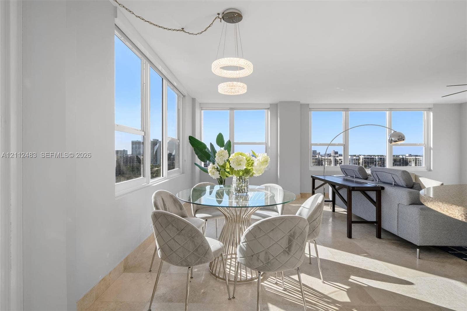 3505 S Ocean Drive, #1101, Hollywood, FL 33019 Open-concept interior featuring large-format stone flooring, floor-to-ceiling windows, and dual circular LED pendant lighting