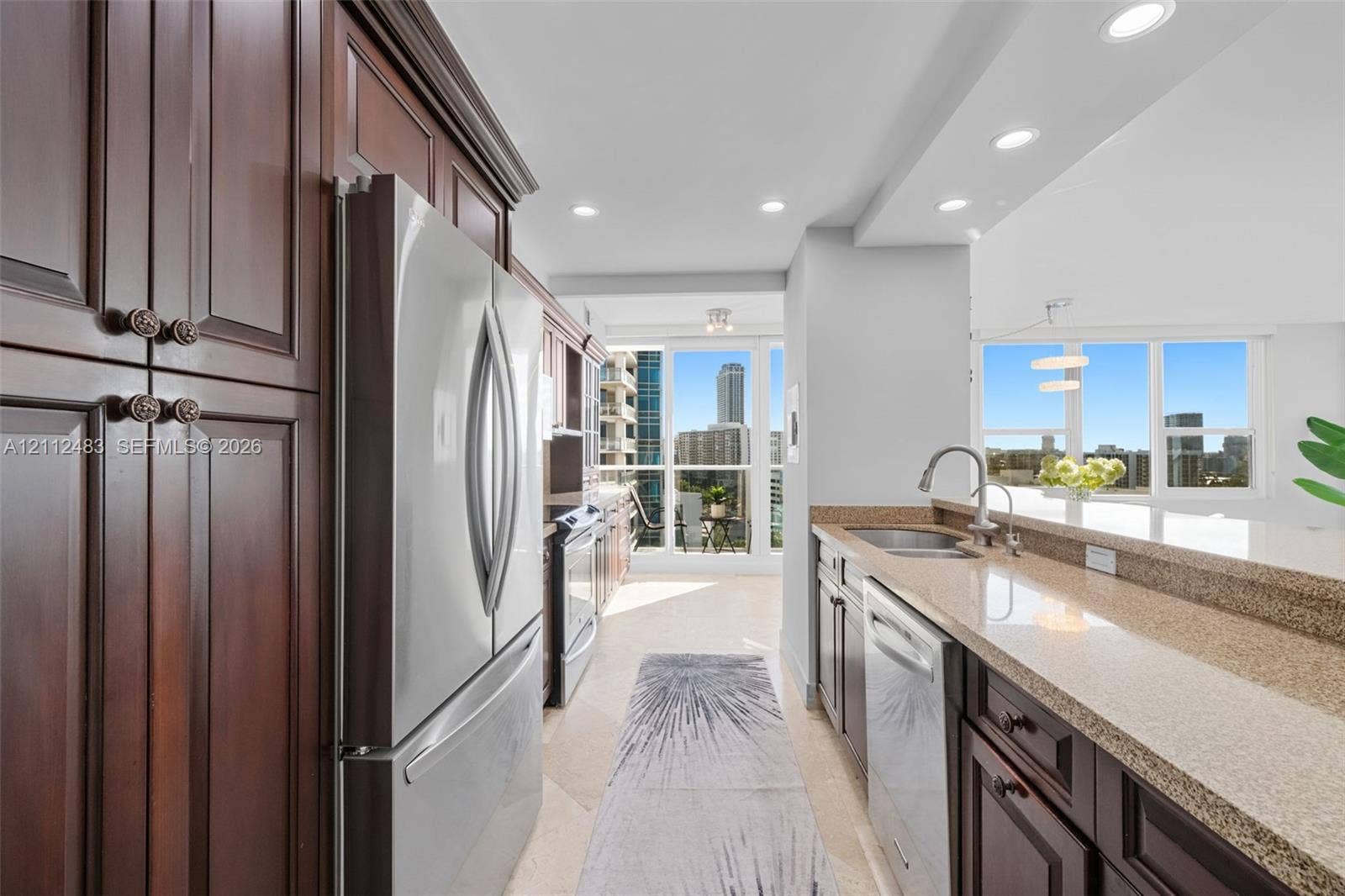 3505 S Ocean Drive, #1101, Hollywood, FL 33019 Kitchen featuring dark wood cabinetry, stainless steel appliances, stone countertops, recessed lighting, and large windows with urban scenery
