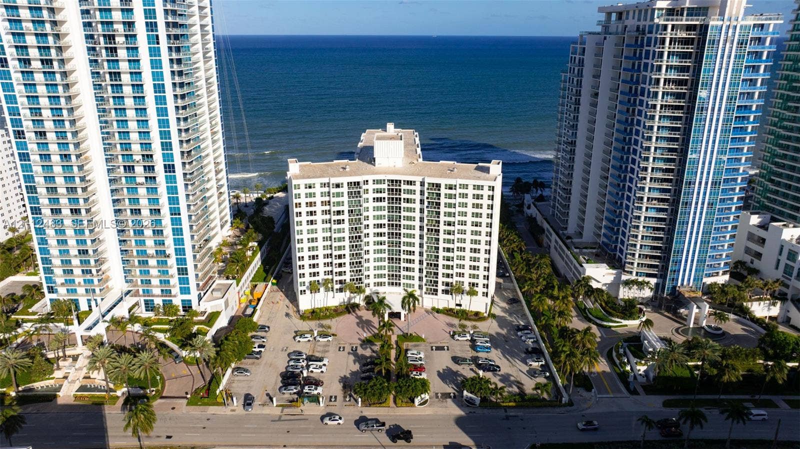 3505 S Ocean Drive, #1101, Hollywood, FL 33019 Mid-rise residential building featuring a concrete exterior, expansive glass windows, ground-level parking, and direct oceanfront positioning