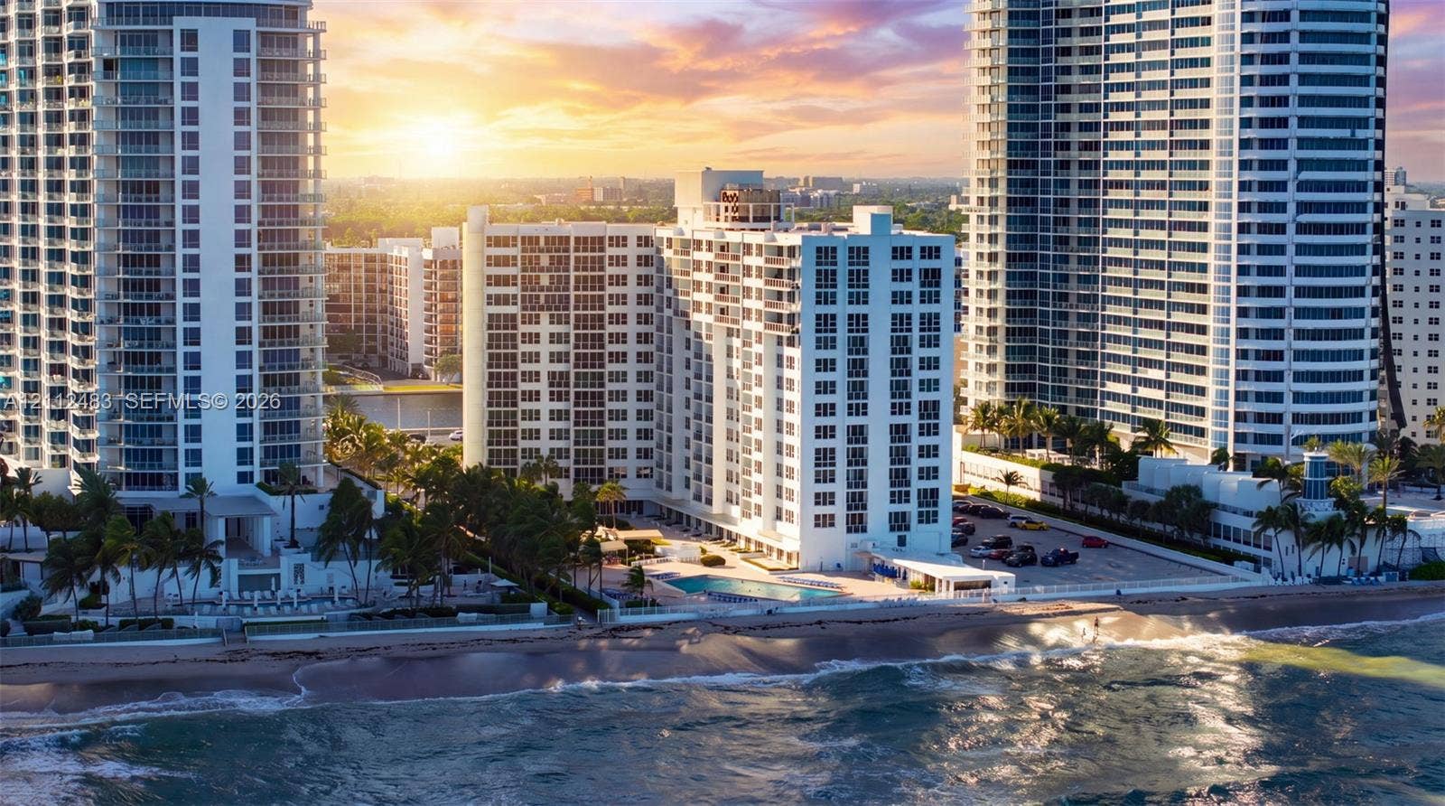 3505 S Ocean Drive, #1101, Hollywood, FL 33019 High-rise building exterior featuring direct oceanfront positioning, ground-level pool, paved surface parking, and mature palm landscaping