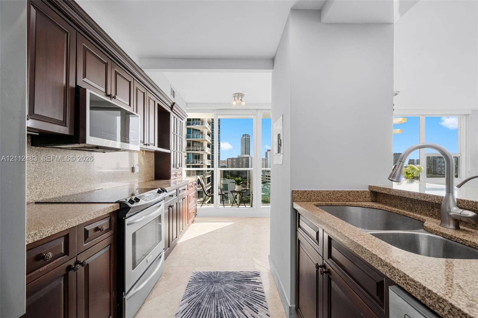 3505 S Ocean Drive, #1101, Hollywood, FL 33019 Kitchen featuring dark wood cabinetry, stone countertops, stainless steel appliances, a double-basin undermount sink with a gooseneck faucet, and floor-to-ceiling windows