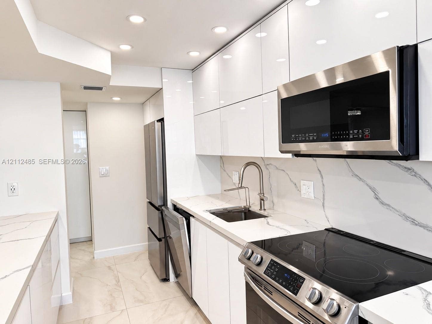 250 174th Street, #1707, Sunny Isles Beach, Sunny Isles Beach, FL 33160 Kitchen featuring high-gloss cabinetry, veined stone-surface countertops, full-height matching backsplash, integrated stainless steel appliances, and recessed ceiling lighting