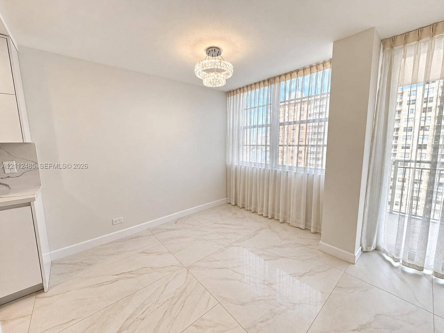 250 174th Street, #1707, Sunny Isles Beach, Sunny Isles Beach, FL 33160 Large-format tile flooring, crystal-accented tiered chandelier, floor-to-ceiling windows, and kitchen cabinetry with quartz-patterned countertops