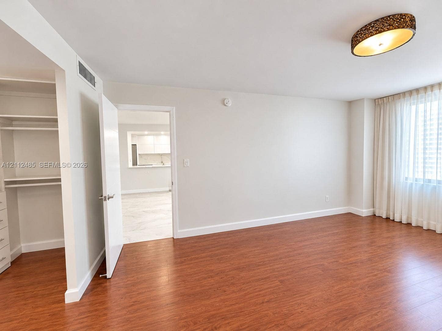 250 174th Street, #1707, Sunny Isles Beach, Sunny Isles Beach, FL 33160 Wood-finish flooring, built-in shelving unit, and decorative semi-flush mount ceiling fixture