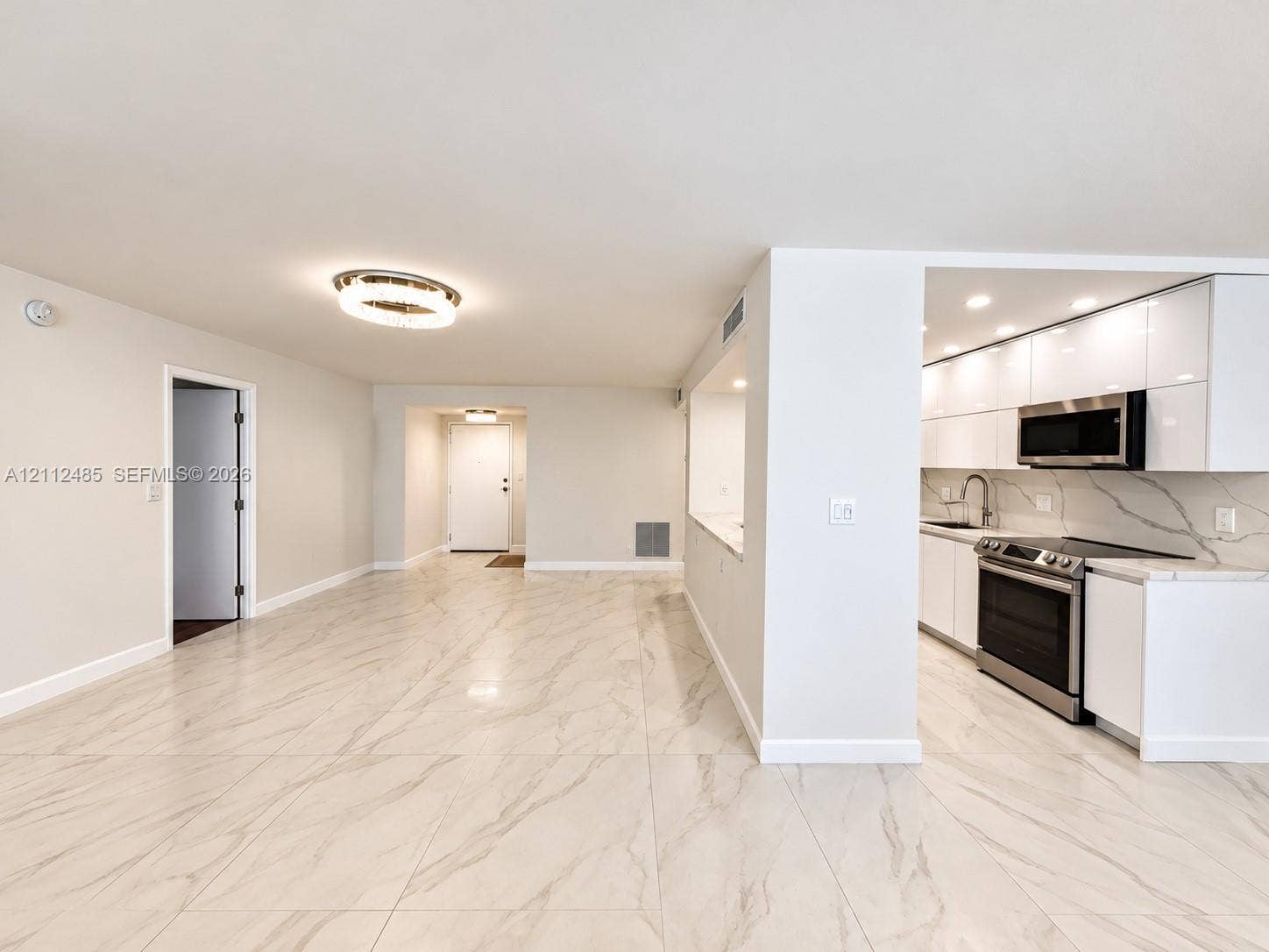 250 174th Street, #1707, Sunny Isles Beach, Sunny Isles Beach, FL 33160 Open-concept floor plan featuring large-format stone-finish flooring, high-gloss white cabinetry, integrated stainless steel appliances, and minimalist ceiling-mounted lighting
