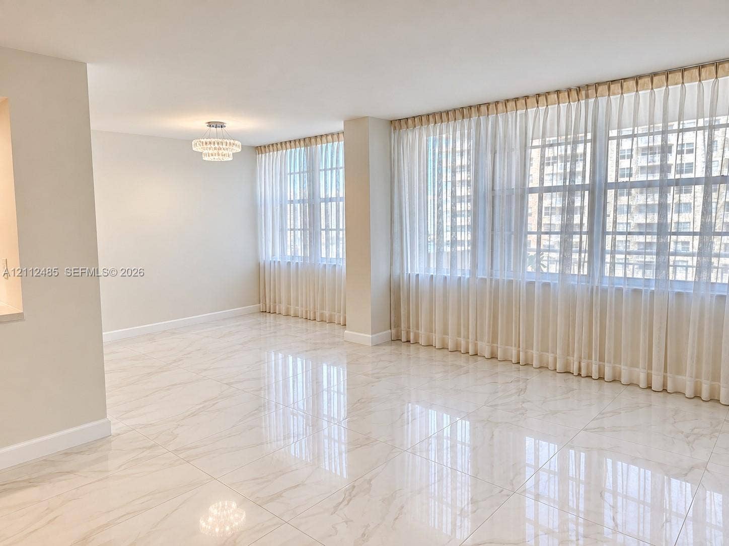 250 174th Street, #1707, Sunny Isles Beach, Sunny Isles Beach, FL 33160 Large-format neutral stone-finish tile flooring, expansive windows with wall-to-wall drapery, and a tiered crystal-style flush-mount ceiling fixture