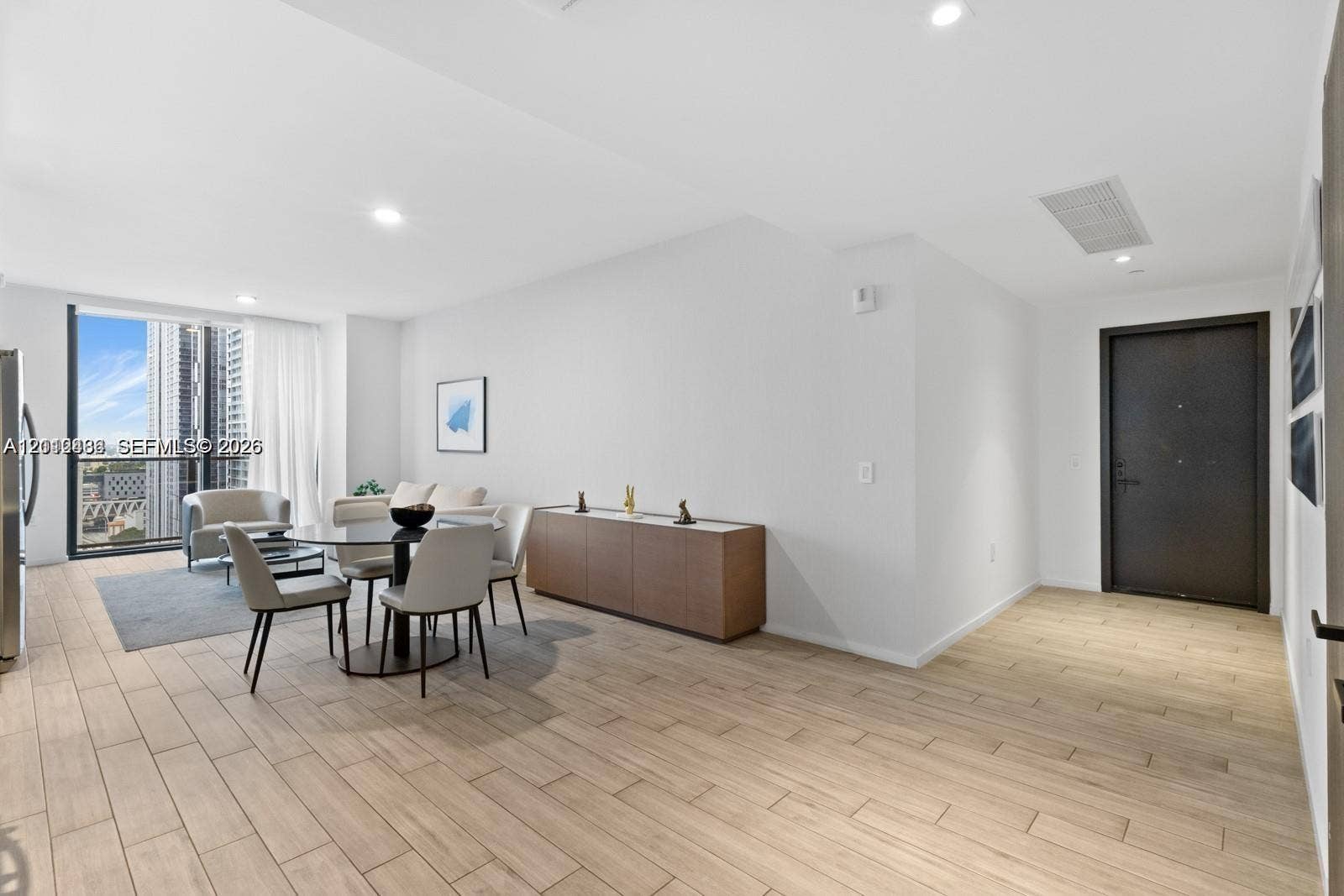Open-concept area featuring wood-finish tile flooring, recessed ceiling lighting, and floor-to-ceiling windows