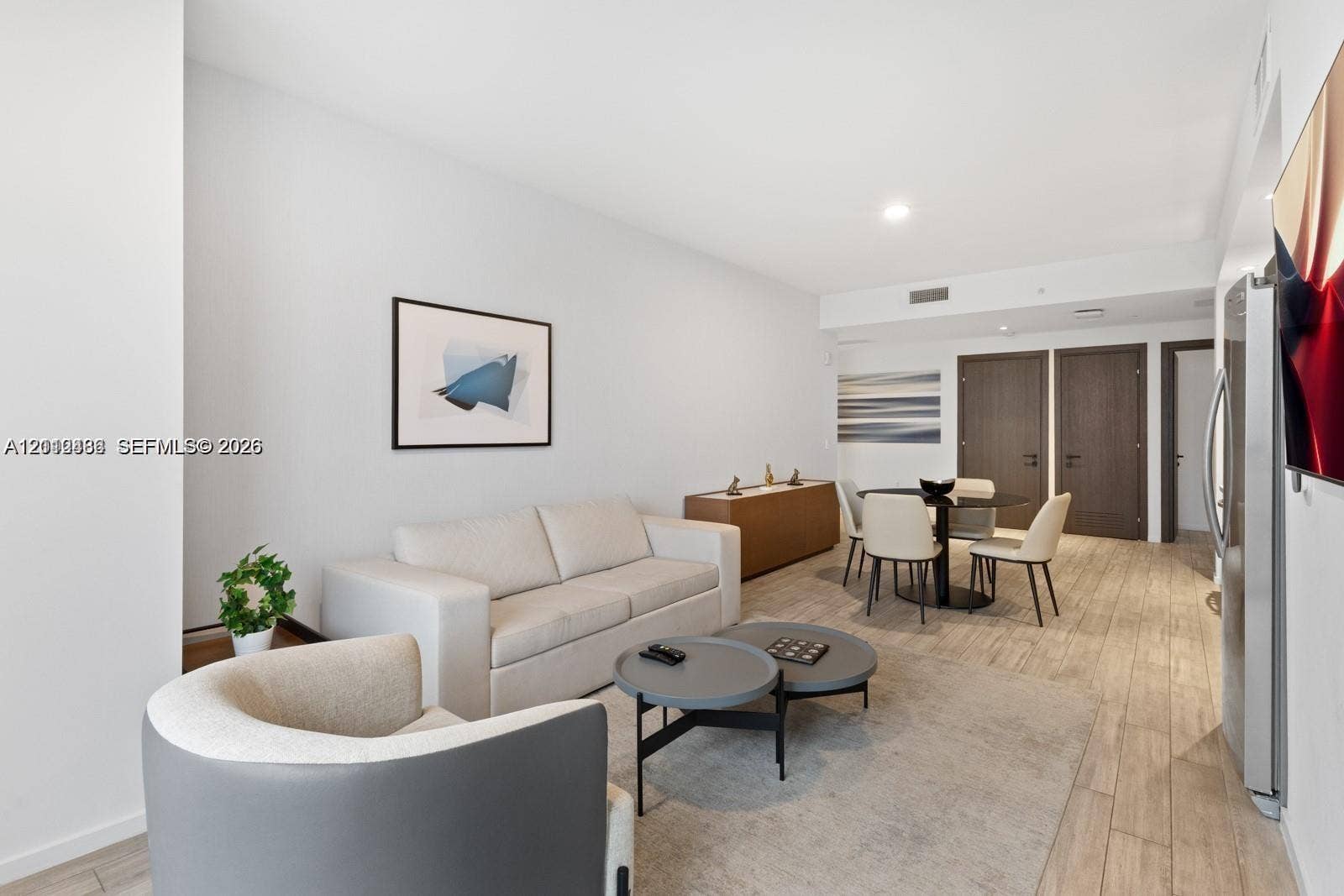 Open-concept interior featuring wood-finish flooring, recessed lighting, and dark-toned interior doors