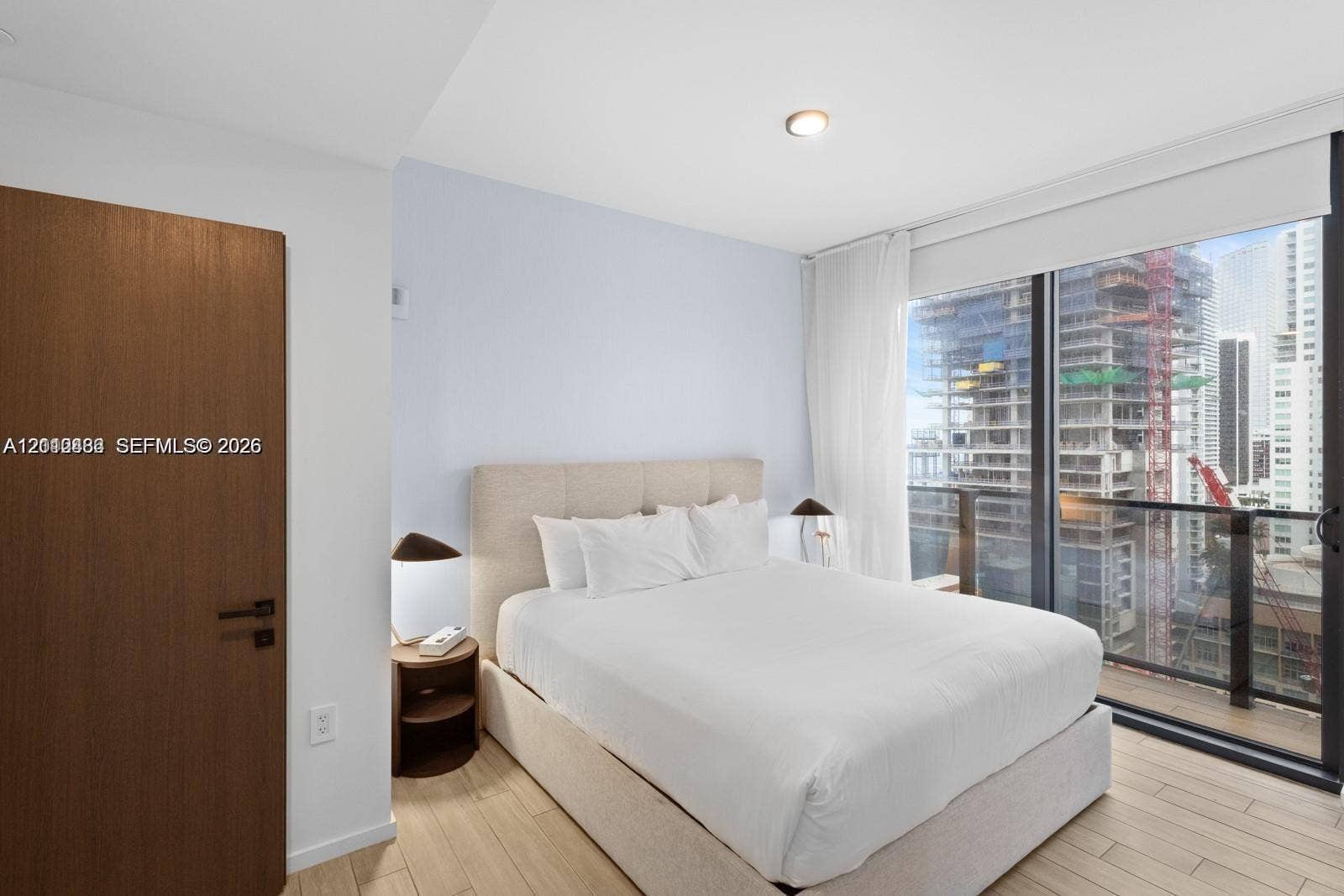 Floor-to-ceiling windows, wood-finish flooring, and a solid wood-finish door with matte black hardware