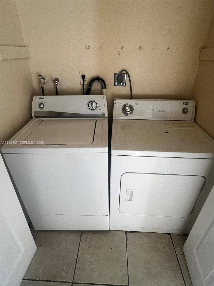 Laundry area featuring side-by-side washer and dryer units with a tiled floor