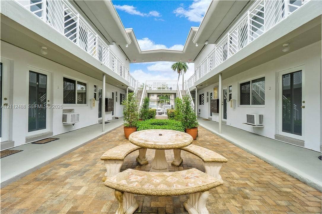 Courtyard area featuring brick paver flooring, stone masonry seating, metal lattice railings, and exterior walkways