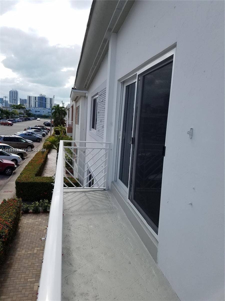 Exterior balcony featuring white metal railings and a sliding glass door
