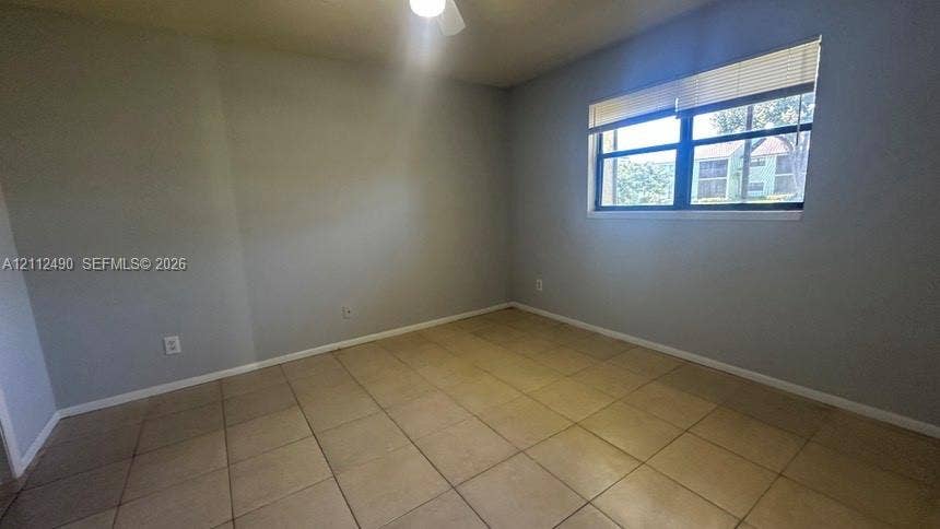 4025 NW 87th Avenue, #4025, Sunrise, Sunrise, FL 33351 Neutral-toned interior featuring ceramic tile flooring, a dual-pane window with integrated horizontal blinds, and a ceiling fan with light fixture