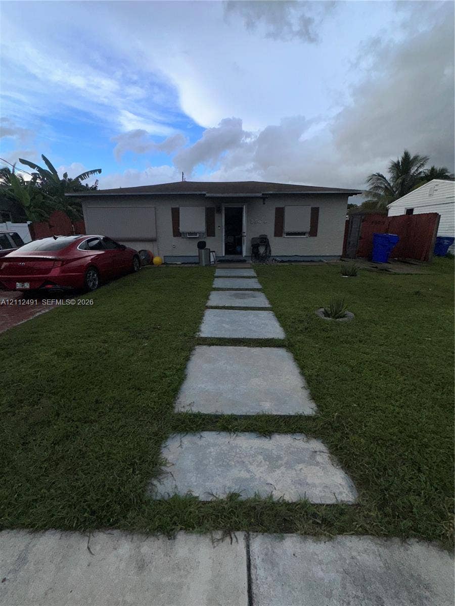 2509 Grant Street, Hollywood, FL 33020 Single-story residence featuring a concrete paver walkway, wood-finish exterior window shutters, and a concrete driveway