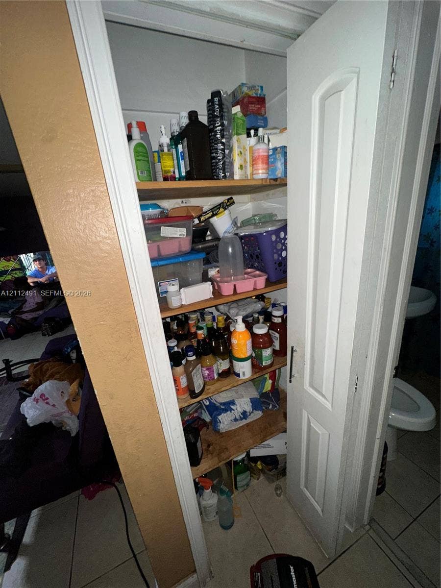 2509 Grant Street, Hollywood, FL 33020 Built-in floor-to-ceiling storage closet featuring a six-panel white door and multiple interior wooden shelves