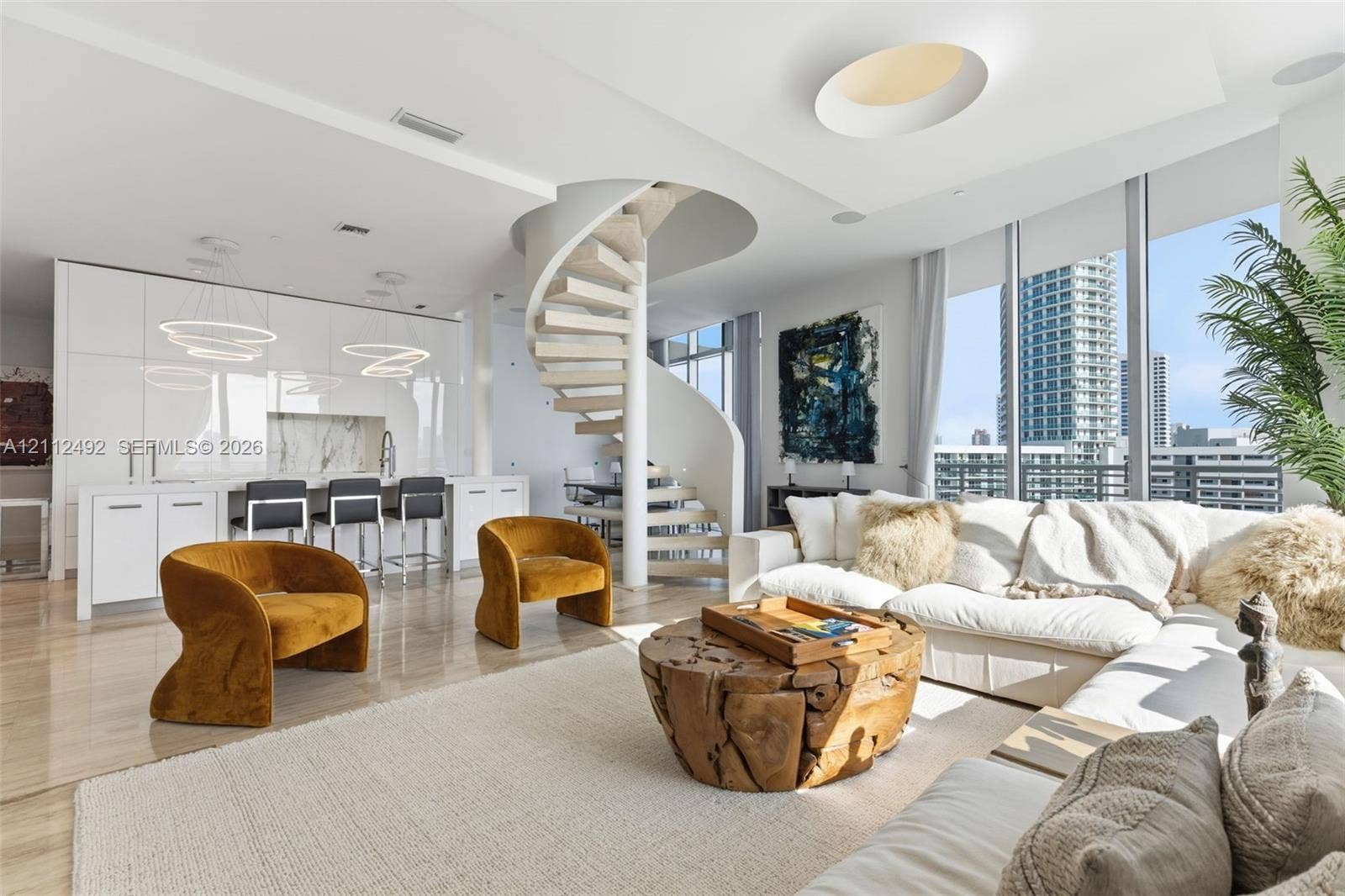 Open-concept living space featuring a sculptural spiral staircase, high-gloss flat-panel cabinetry, floor-to-ceiling windows, and polished stone flooring