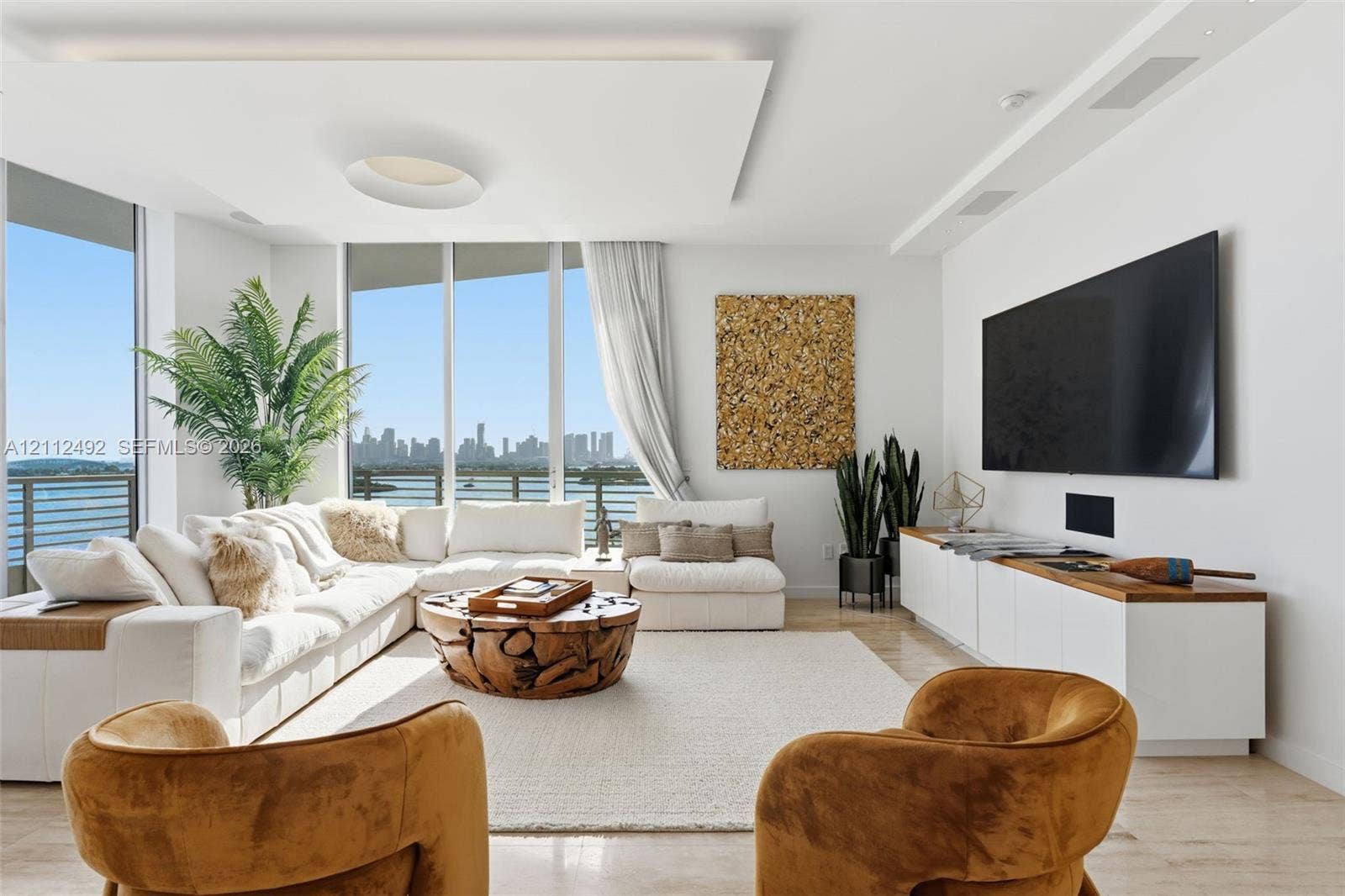 Living area featuring floor-to-ceiling windows, custom recessed tray ceiling with integrated lighting, polished stone flooring, and built-in low-profile cabinetry