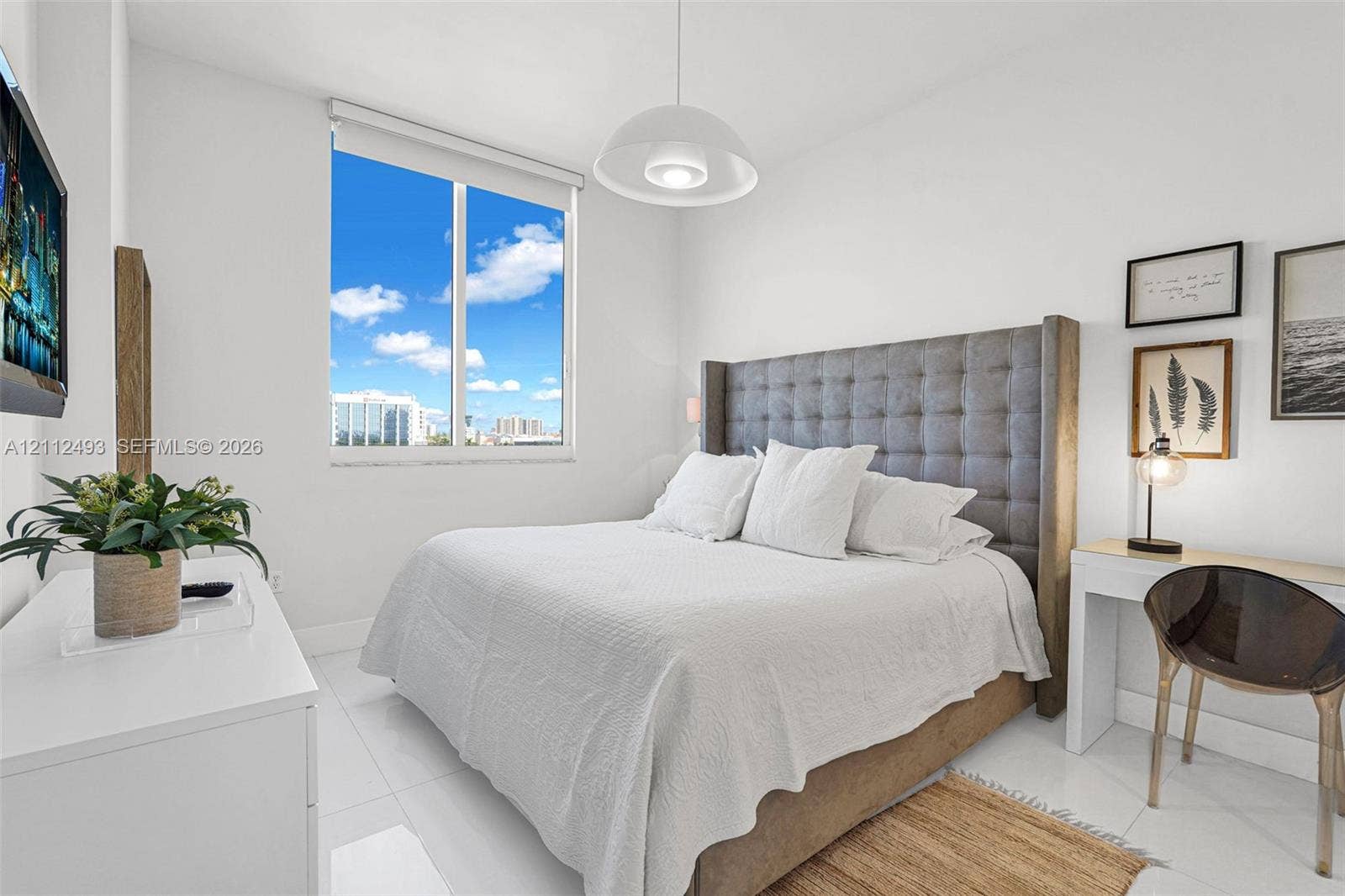 Large picture window with exterior scenery, neutral walls, white floor tiling, and a central pendant light fixture