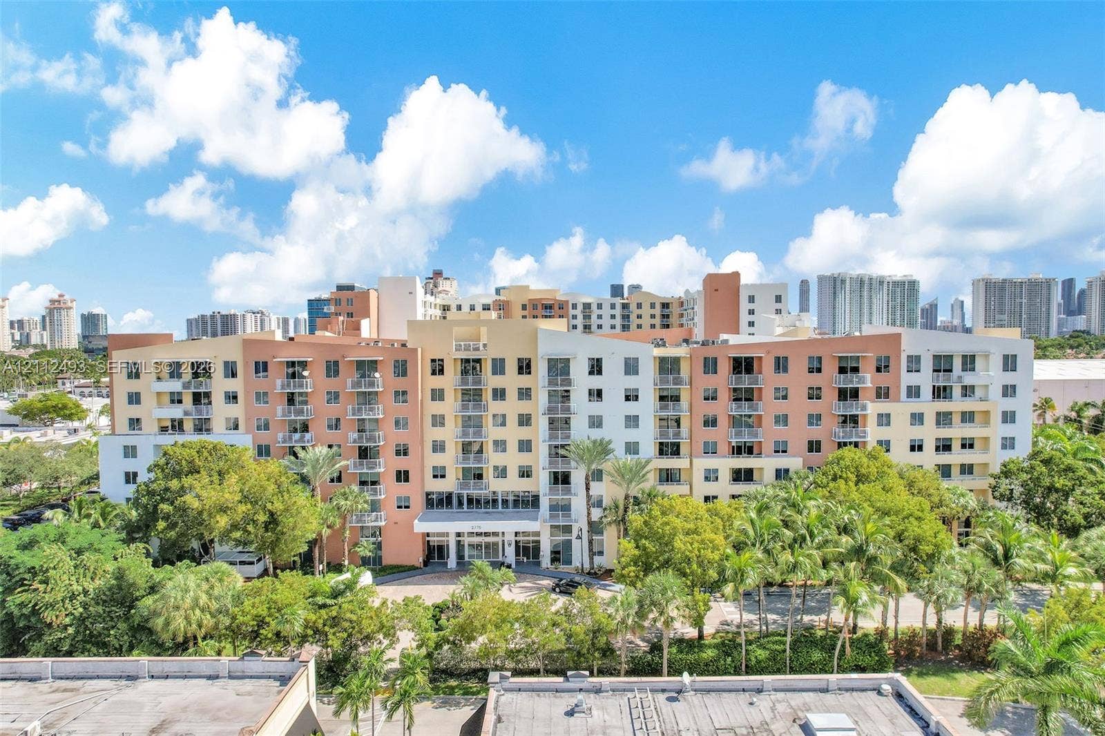 Multi-story residential complex featuring private balconies, expansive glass fenestration, and mature perimeter landscaping