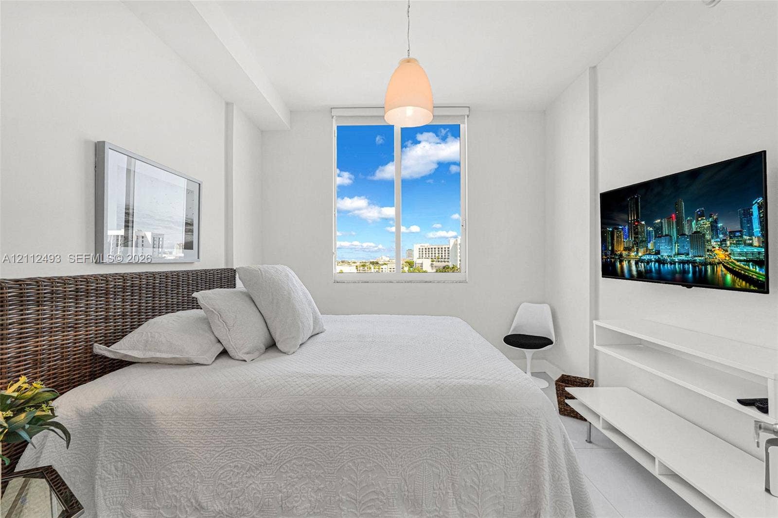 Bright interior featuring a single-light pendant fixture, white wall-mounted tiered shelving, and a large single-pane window with expansive exterior scenery