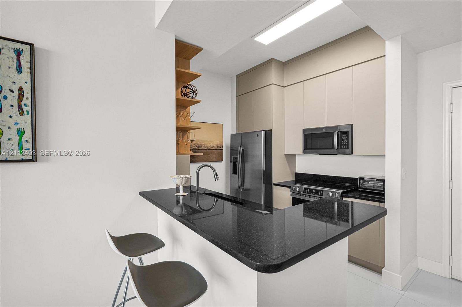 Kitchen featuring dark stone countertops, integrated cabinetry, stainless steel appliances, and built-in floating shelving