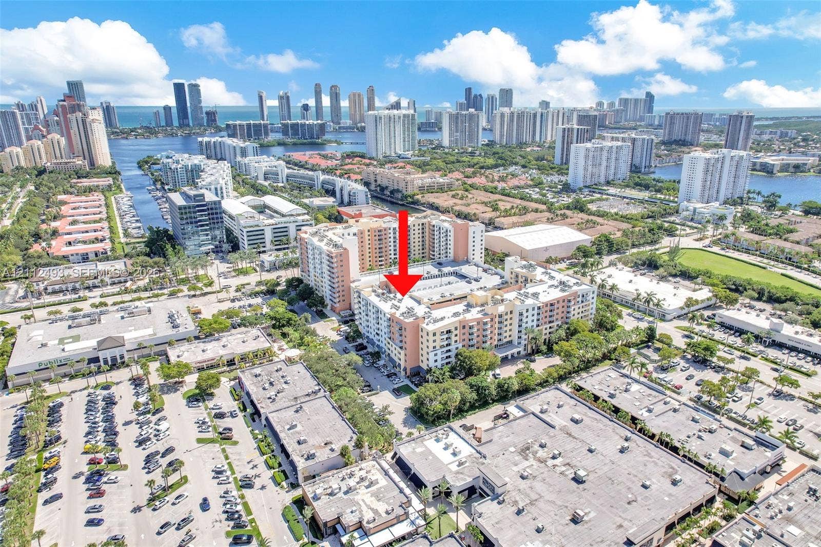Aerial perspective of a multi-story residential building featuring a stucco exterior and flat roofline, positioned within a high-density urban environment