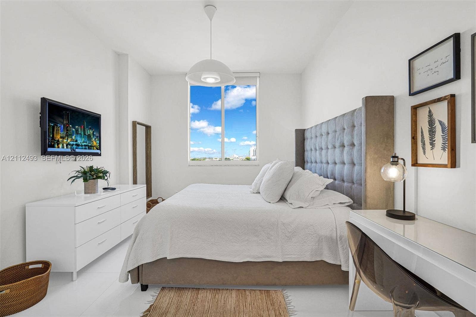 Bright room featuring high ceilings, a large single-pane window, and white tile flooring