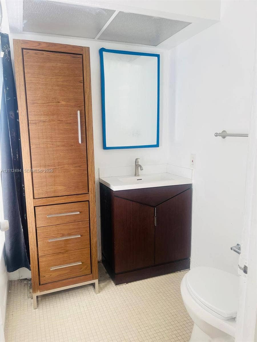 7364 SW 82nd Street, #E207, Miami, Miami, FL 33143 Bathroom featuring a dark wood-finish vanity with an integrated basin, a tall matching wood-finish storage cabinet, and a wall-mounted mirror