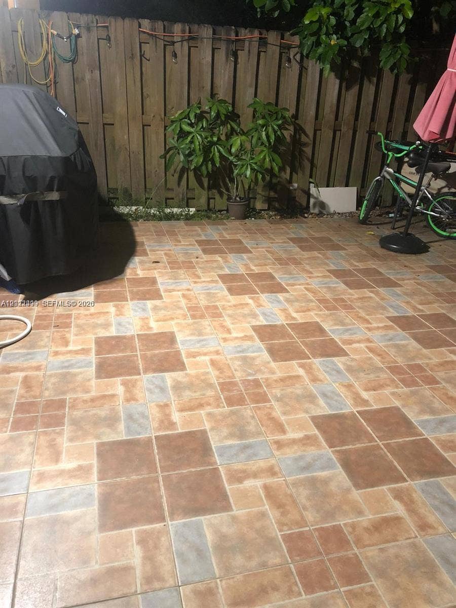 Paved patio featuring multi-toned square tiles and a wood-slat privacy fence