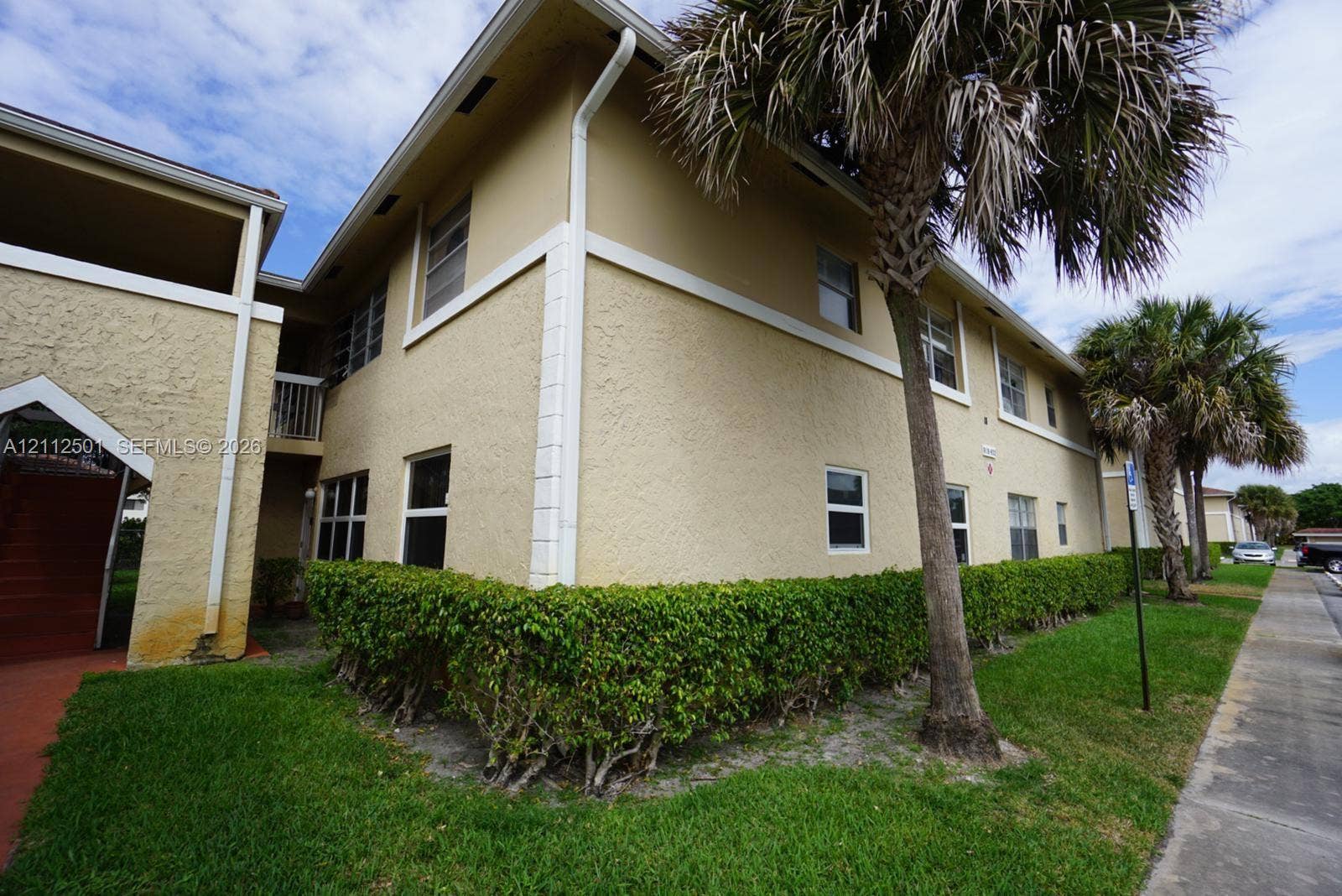 Two-story exterior featuring a textured stucco finish, white corner quoins, and horizontal sliding windows