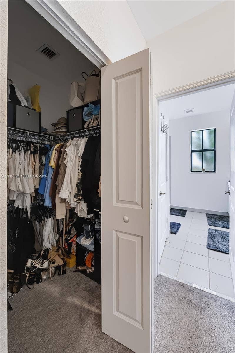 538 SW 19th Terrace, Fort Lauderdale, Fort Lauderdale, FL 33312 Walk-in closet featuring built-in wire shelving, paired with an entry area showcasing white tile flooring and a multi-pane window