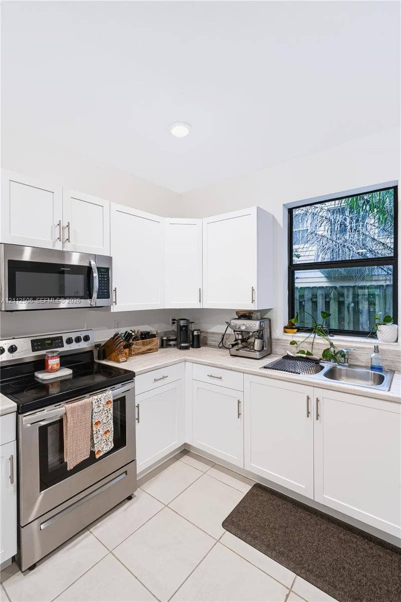 538 SW 19th Terrace, Fort Lauderdale, Fort Lauderdale, FL 33312 Kitchen featuring white shaker-style cabinetry, stainless steel appliances, neutral stone-finish countertops, tile flooring, and a single-basin undermount sink