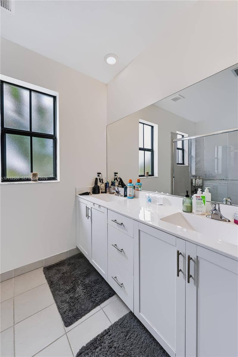 538 SW 19th Terrace, Fort Lauderdale, Fort Lauderdale, FL 33312 Dual-sink vanity featuring white shaker-style cabinetry, solid-surface countertop, integrated rectangular sinks, and large wall-mounted mirror