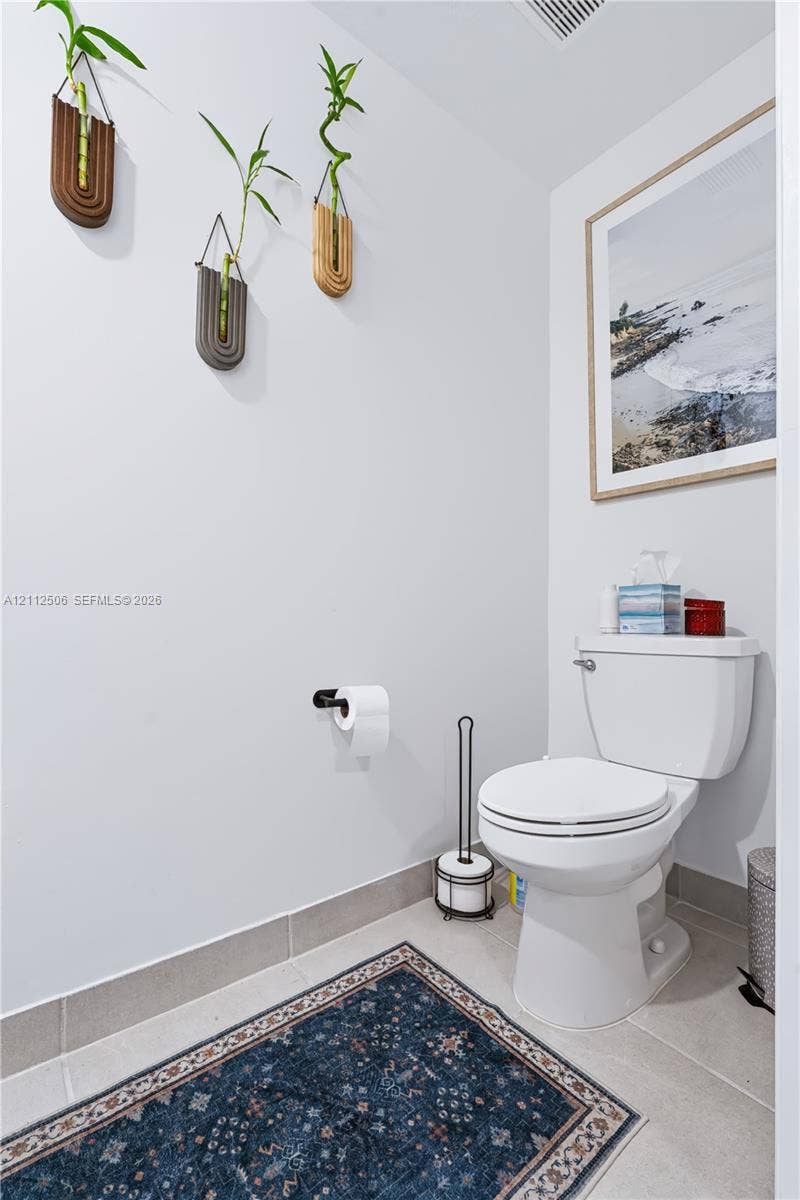 538 SW 19th Terrace, Fort Lauderdale, Fort Lauderdale, FL 33312 Neutral-toned restroom featuring a white porcelain commode, matte black wall-mounted toilet paper holder, and large-format tile flooring