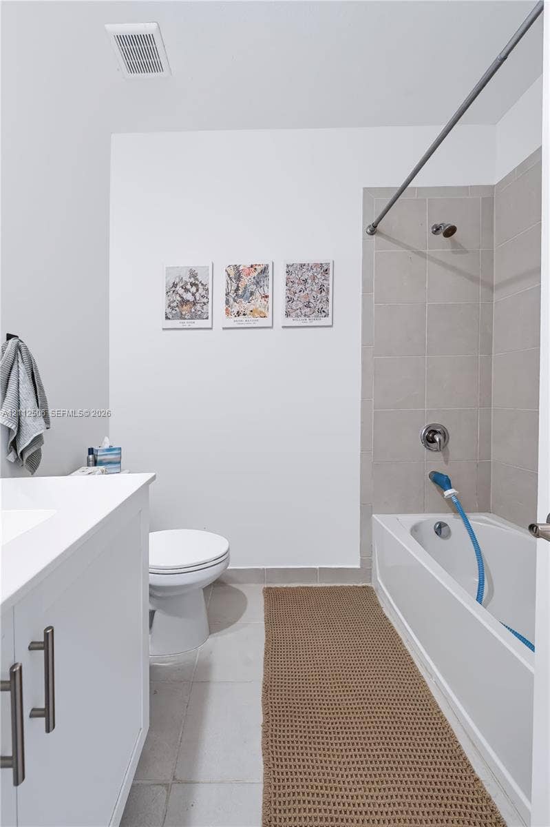 538 SW 19th Terrace, Fort Lauderdale, Fort Lauderdale, FL 33312 Bathroom featuring a white vanity cabinet with metallic hardware, a white porcelain toilet, and a bathtub with neutral-toned wall tile surround