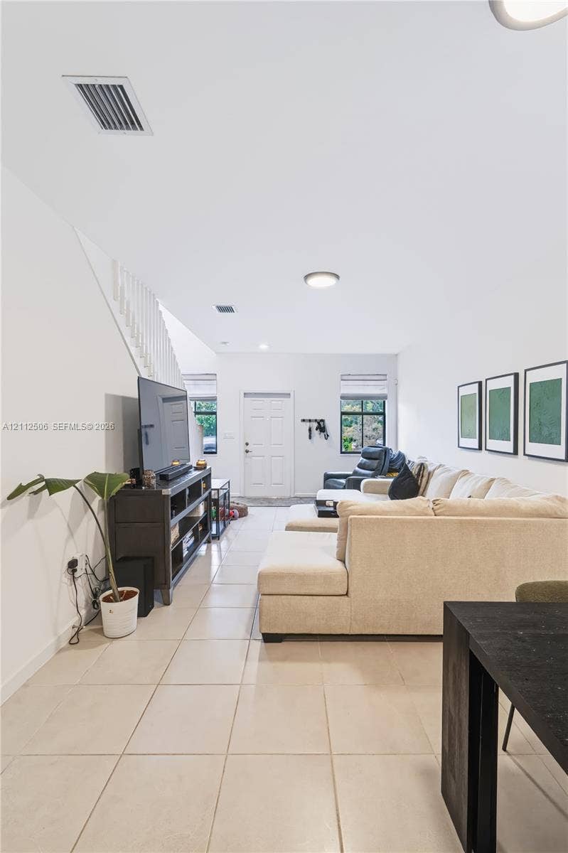 538 SW 19th Terrace, Fort Lauderdale, Fort Lauderdale, FL 33312 Open-concept interior featuring neutral ceramic tile flooring, a white staircase with a vertical balustrade, and dual windows