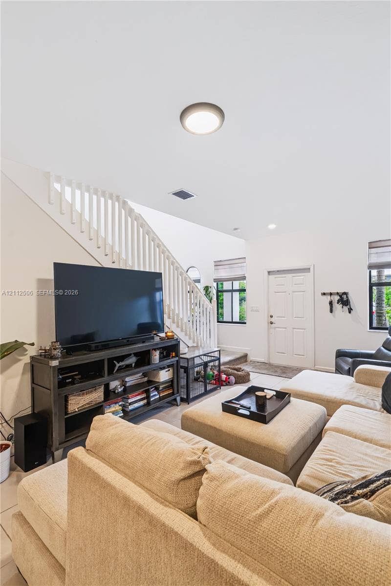 538 SW 19th Terrace, Fort Lauderdale, Fort Lauderdale, FL 33312 Open-concept interior featuring high ceilings, wood-finish flooring, a white staircase with a wooden handrail, and windows with integrated blinds